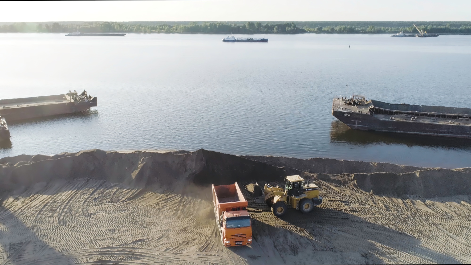 Excavator clearing beach. Scene. Top view of clearing of beach area. Excavator and dump trucks clean