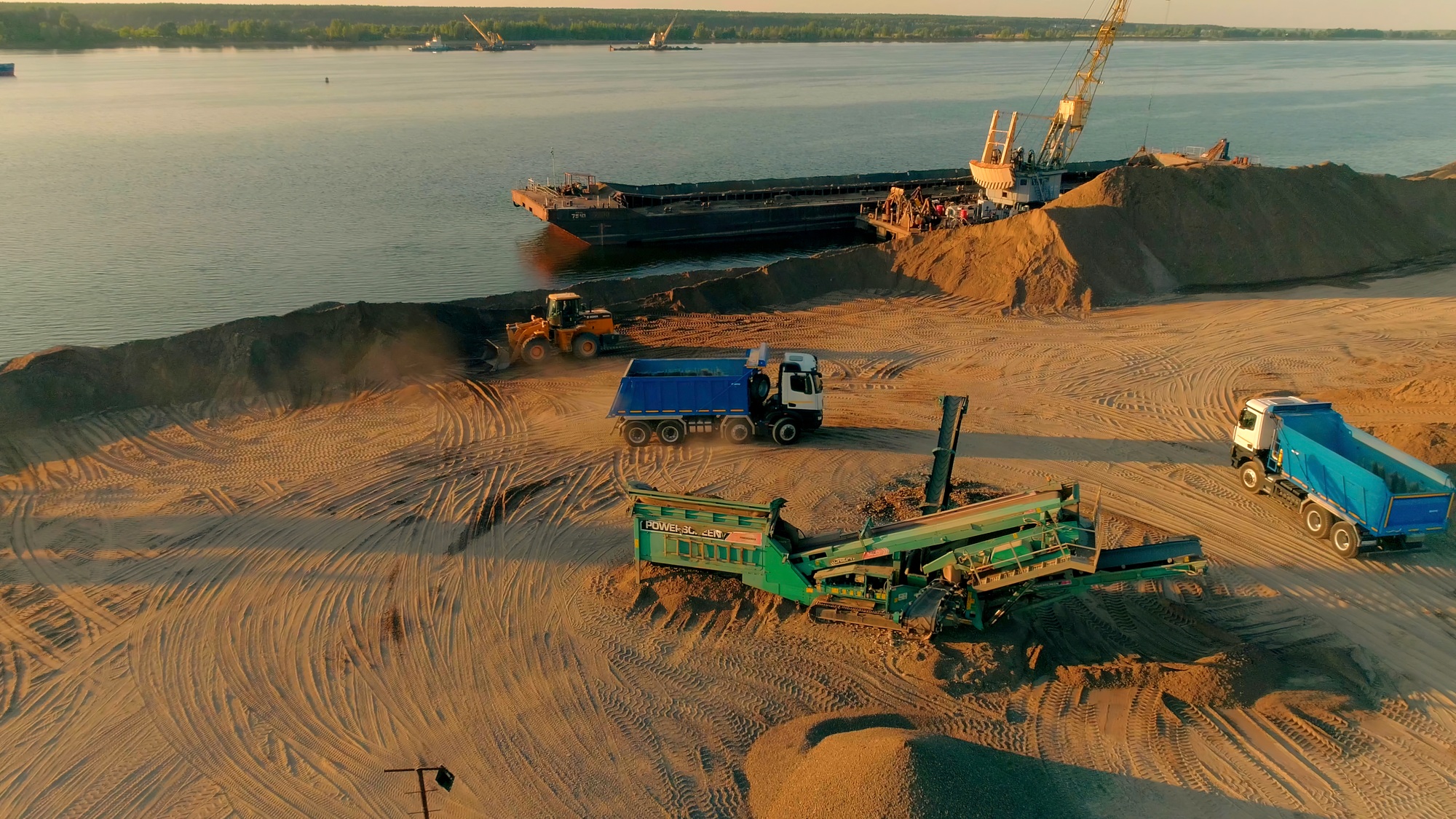 Excavator , trucks and cranes working at the construction site. Scene. Sand quarry and the river on
